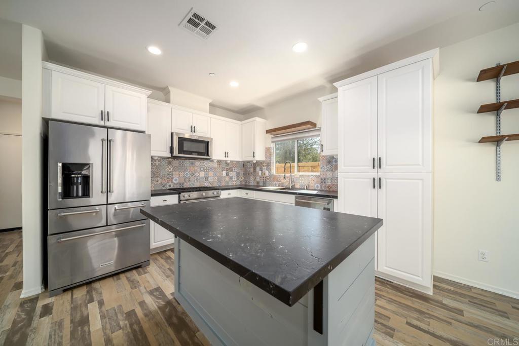 313 Dun Blazer Way Fallbrook, CA 92028 - Photo 12 of 59 a kitchen with kitchen island a counter top space a refrigerator a sink and cabinets