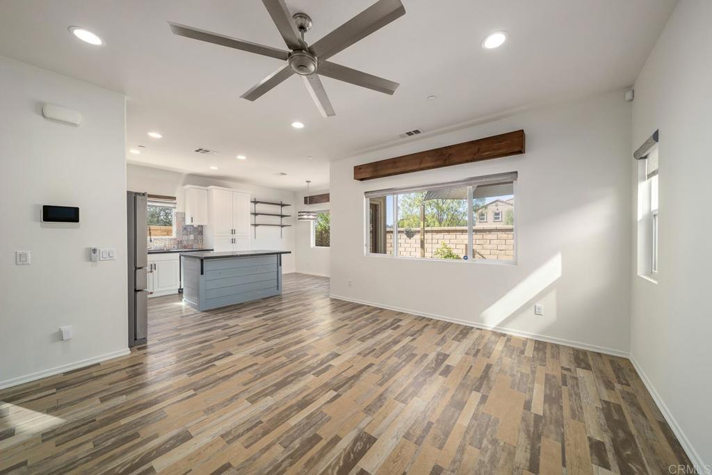 313 Dun Blazer Way Fallbrook, CA 92028 - Photo 5 of 59 an empty room with wooden floor a ceiling fan and kitchen view