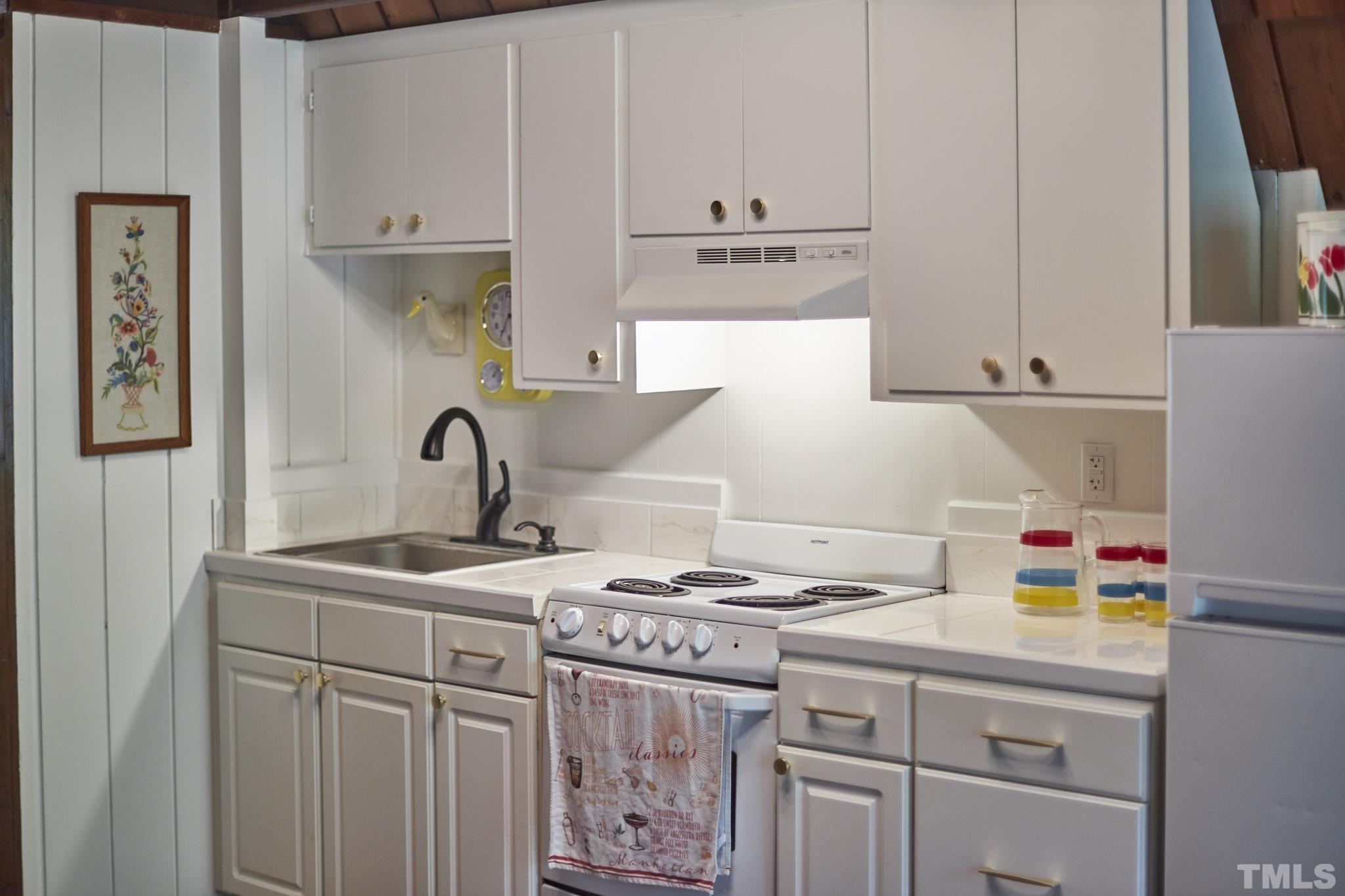 1002 Wave Road Chapel Hill, NC 27517 - Photo 22 of 43 a kitchen with kitchen island a sink a stove and white cabinets