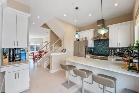 a kitchen with stainless steel appliances kitchen island granite countertop a stove a sink a oven a dining table and chairs with wooden floor