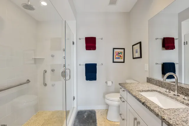 a bathroom with a granite countertop sink mirror vanity and toilet