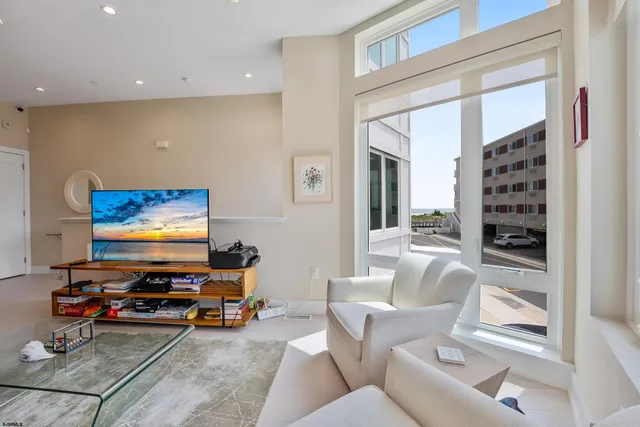 a living room with furniture a flat screen tv and a floor to ceiling window
