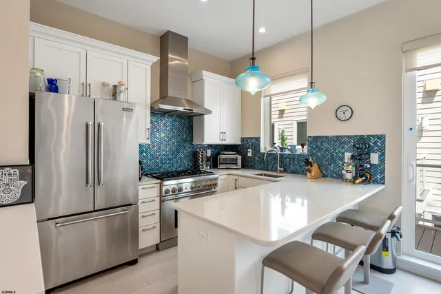 a kitchen with stainless steel appliances granite countertop a refrigerator a oven a sink a stove and a chandelier