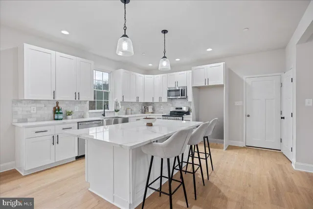a kitchen with stainless steel appliances kitchen island granite countertop a wooden floor and white cabinets