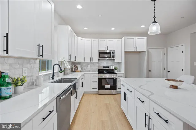 a kitchen with kitchen island sink stove and white cabinets