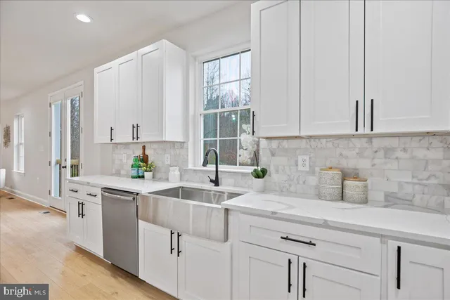 a kitchen with stainless steel appliances white cabinets and a window