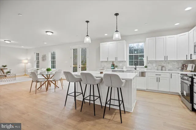 a kitchen with kitchen island granite countertop lots of white cabinets and stainless steel appliances