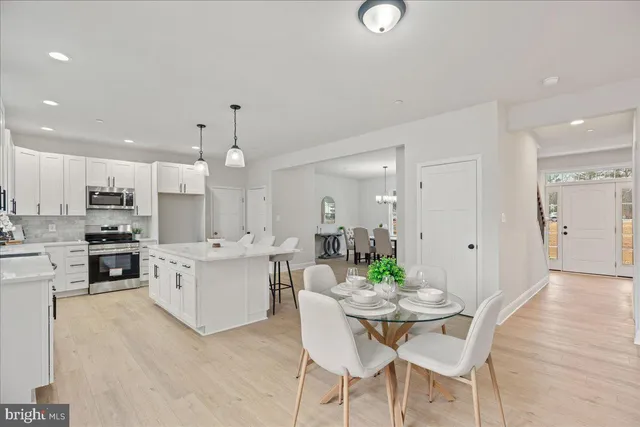 a large white kitchen with a refrigerator a stove a sink a dining table and chairs