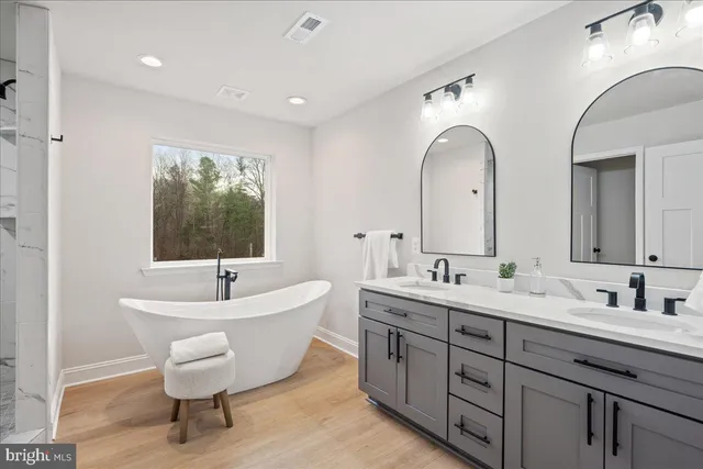 a spacious bathroom with a double vanity sink mirror and bathtub