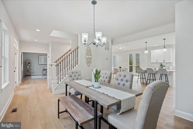 a view of a dining room and livingroom with furniture wooden floor a chandelier