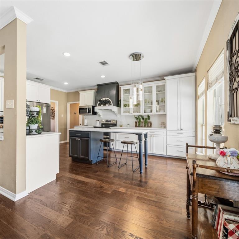785 Tweedy Road Valley Mills, TX 76689 - Photo 9 of 40 Kitchen featuring wood-finish flooring, white cabinetry, a central island with seating, a pendant light fixture, and recessed lighting