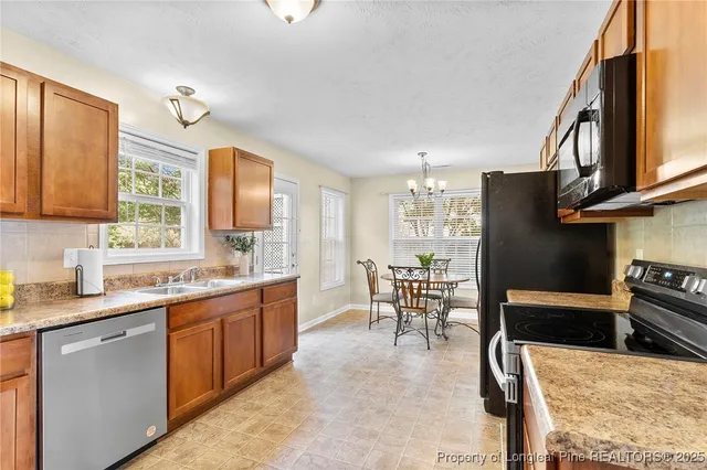 a kitchen with stainless steel appliances granite countertop sink stove refrigerator dining table and chairs