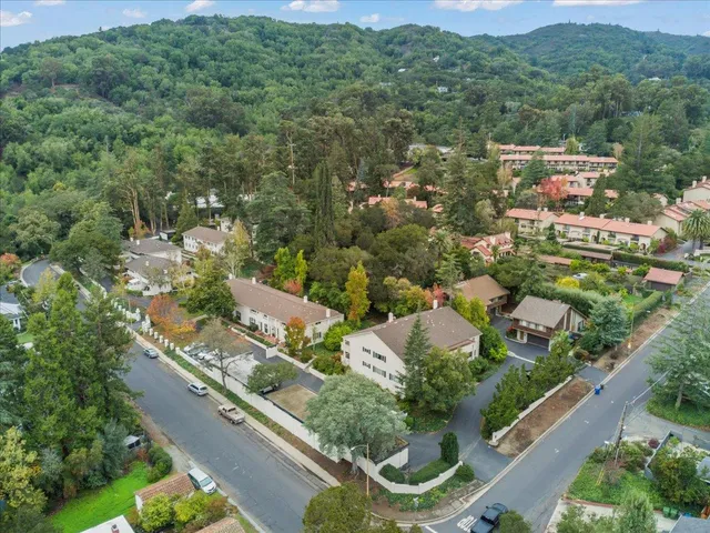 an aerial view of residential houses with outdoor space and trees