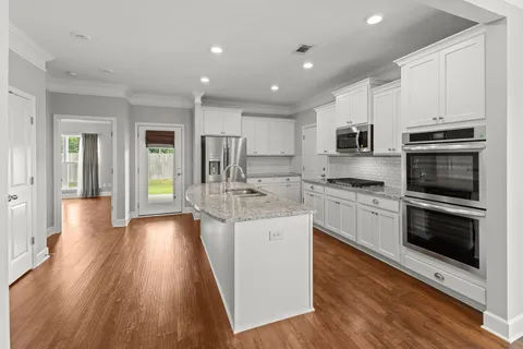 a kitchen with stainless steel appliances kitchen island granite countertop a stove a sink and a refrigerator