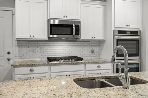 a kitchen with granite countertop a sink and a stove top oven