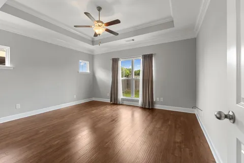 an empty room with wooden floor and ceiling fan