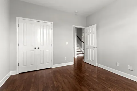 a view of an empty room with wooden floor and closet