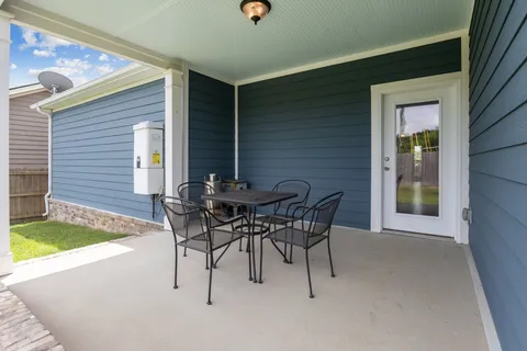 a patio with table and chairs and potted plants
