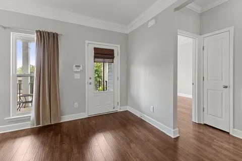a view of an empty room with wooden floor and a window