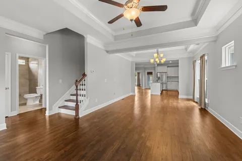 a view of an empty room with wooden floor and a ceiling fan
