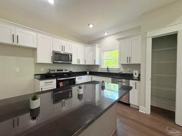 a spacious bathroom with a granite countertop sink a mirror and a shower