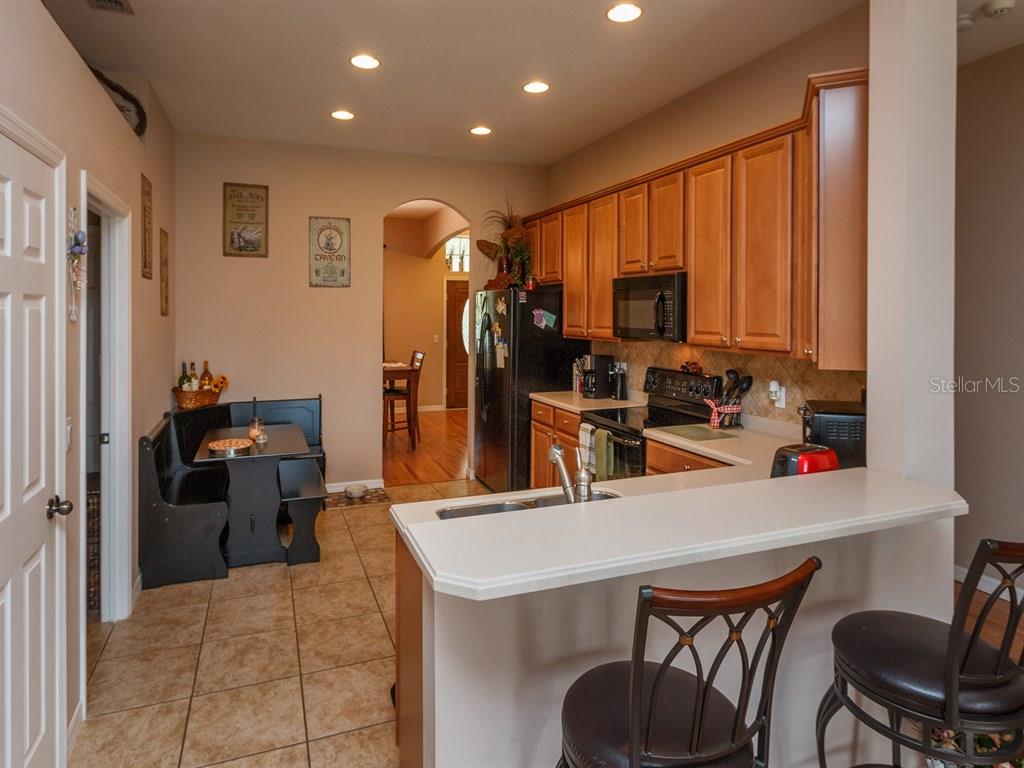 5477 Rishley Run Way Mount Dora, FL 32757 - Photo 6 of 25 a kitchen with stainless steel appliances a stove top oven a refrigerator a sink a dining table and chairs with wooden floor