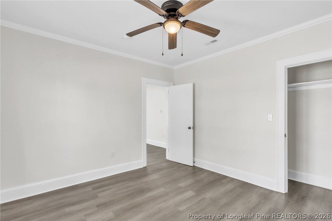 203 Trinity Street Fairmont, NC 28340 - Photo 23 of 34 an empty room with wooden floor chandelier fan and closet area