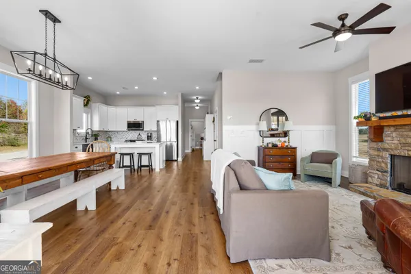 a living room with furniture kitchen view and a wooden floor