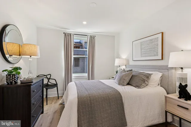 a large bedroom with a bed a mirror and a window