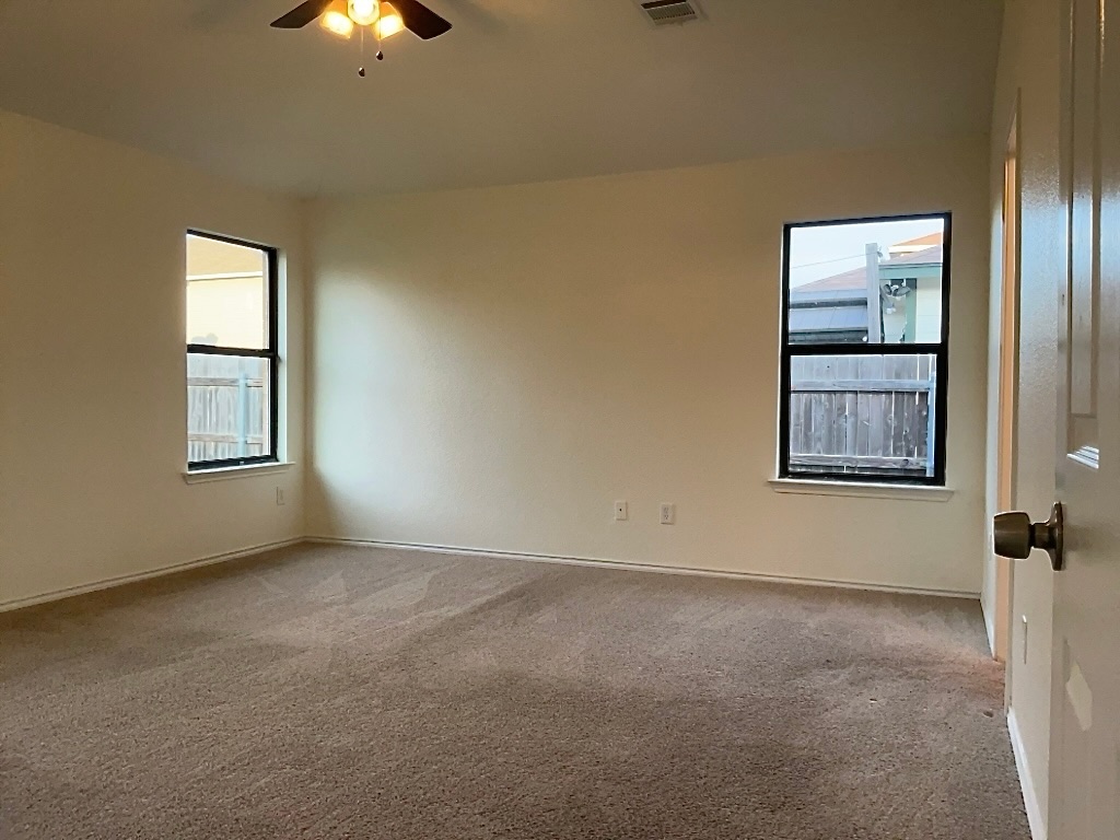 704 Big Sur Trail Taylor, TX 76574 - Photo 11 of 18 Empty room with light carpet, plenty of natural light, and a ceiling fan