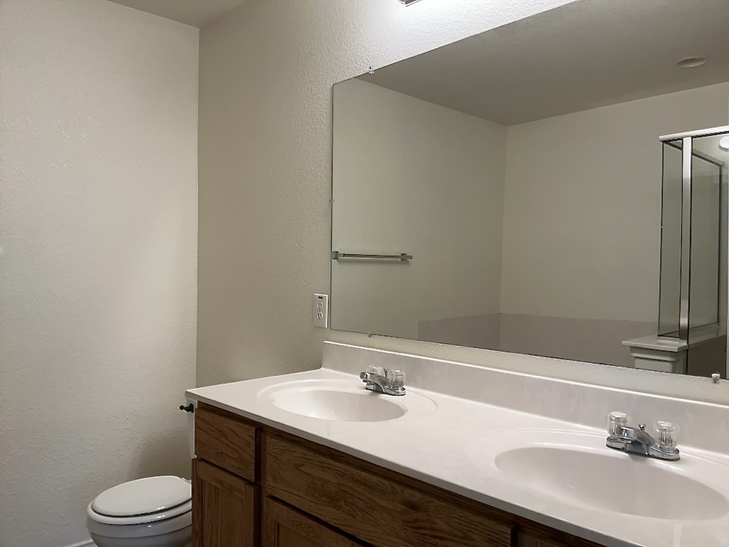 704 Big Sur Trail Taylor, TX 76574 - Photo 13 of 18 Full bath featuring double vanity, a textured wall, and a shower stall