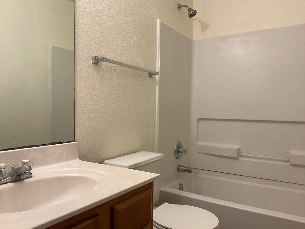 704 Big Sur Trail Taylor, TX 76574 - Photo 15 of 18 Bathroom featuring vanity, shower / bathtub combination, and a textured wall