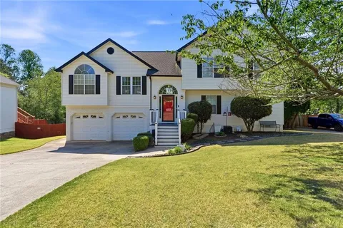 a front view of house with yard and trees in the background