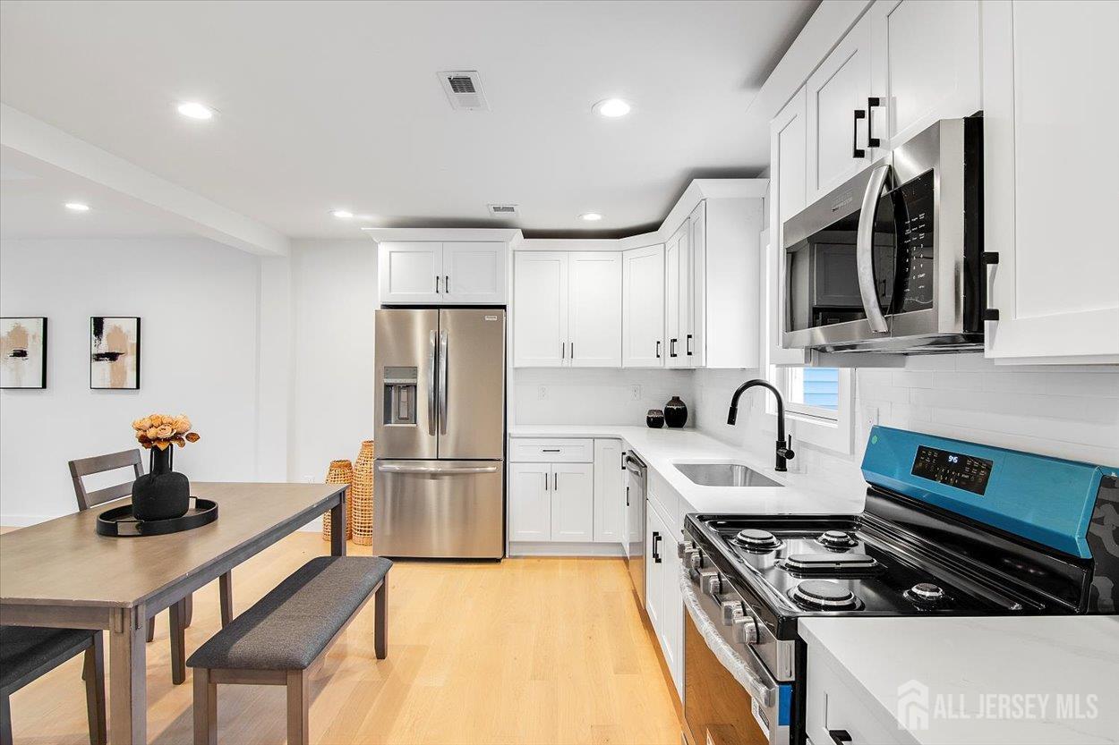 130 Ridge Road Colonia, NJ 07067 - Photo 11 of 28 a kitchen with stainless steel appliances a stove a sink a microwave and cabinets