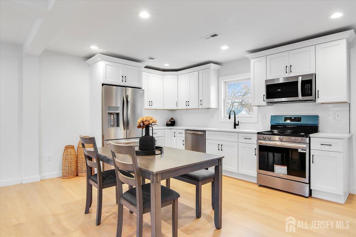 130 Ridge Road Colonia, NJ 07067 - Photo 8 of 28 a kitchen with stainless steel appliances a stove a sink a microwave a refrigerator and cabinets