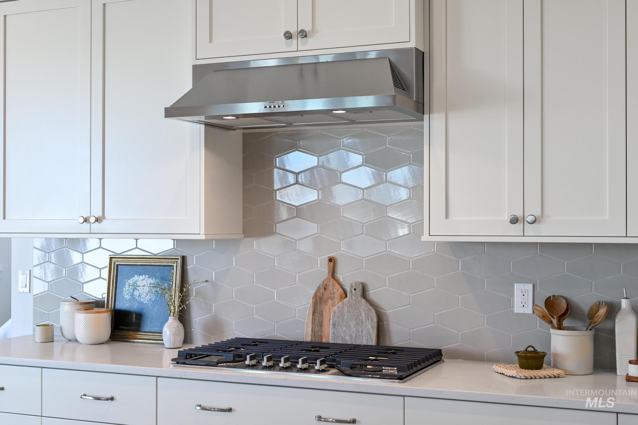 14676 Serenity Pt Street Caldwell, ID 83607 - Photo 11 of 41 Modern kitchen featuring white shaker-style cabinetry, a stainless steel range hood, and a built-in cooktop