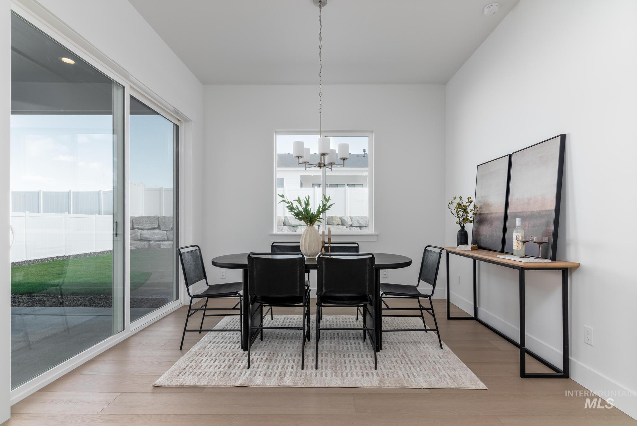 14676 Serenity Pt Street Caldwell, ID 83607 - Photo 17 of 41 Bright dining area featuring wood-finish flooring, a contemporary chandelier, and a large sliding glass door