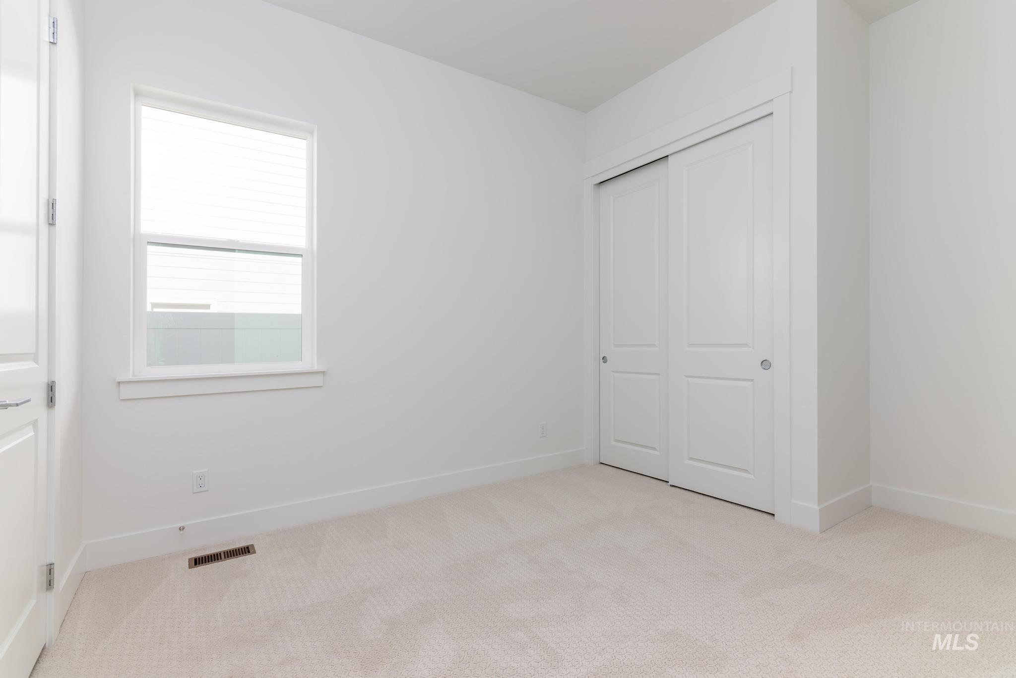 14676 Serenity Pt Street Caldwell, ID 83607 - Photo 25 of 41 Light-filled room featuring a double-paned window, neutral carpeting, white trim, and a bi-fold closet with panel doors