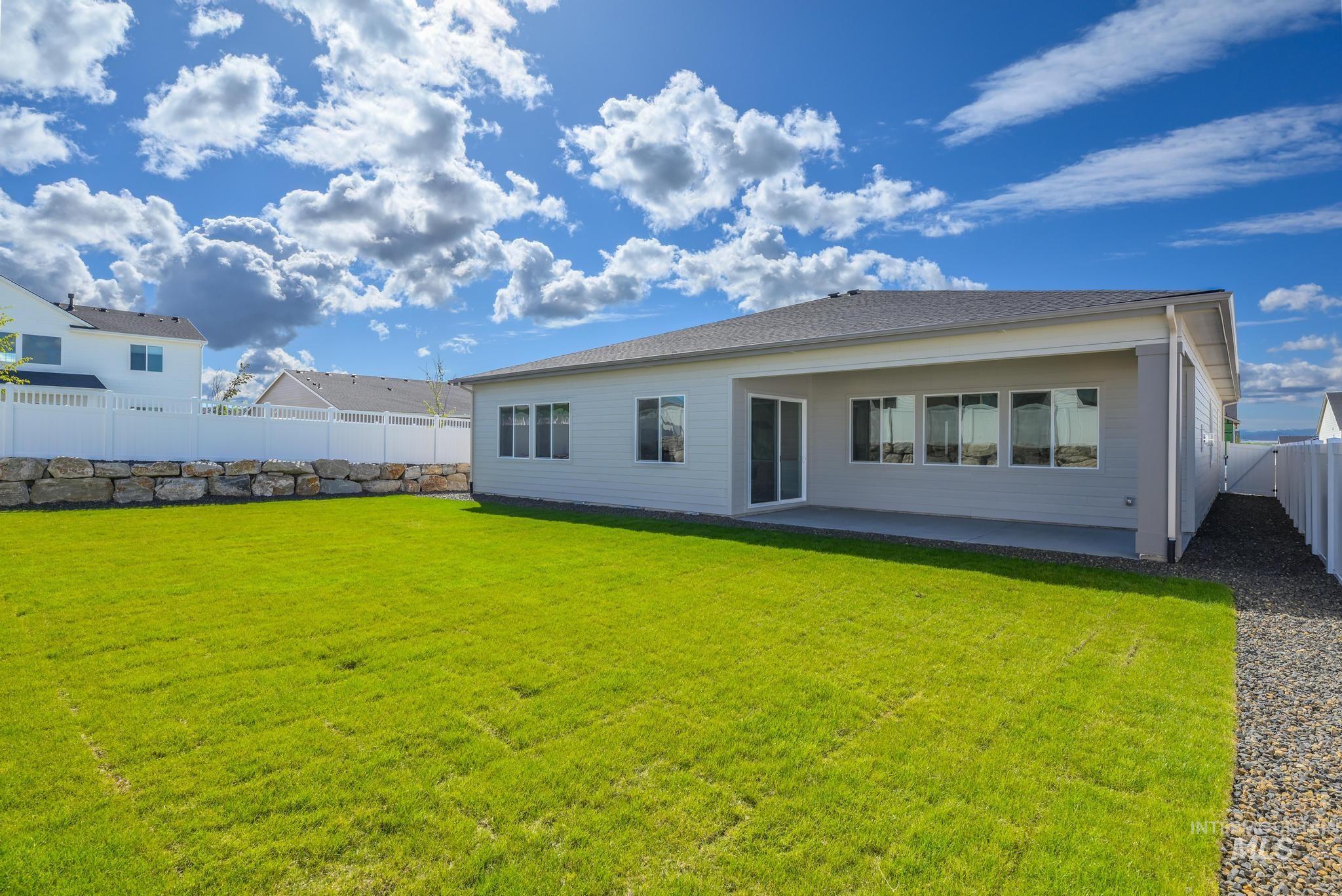 14676 Serenity Pt Street Caldwell, ID 83607 - Photo 30 of 41 Expansive green lawn with a white vinyl privacy fence and a stone retaining wall