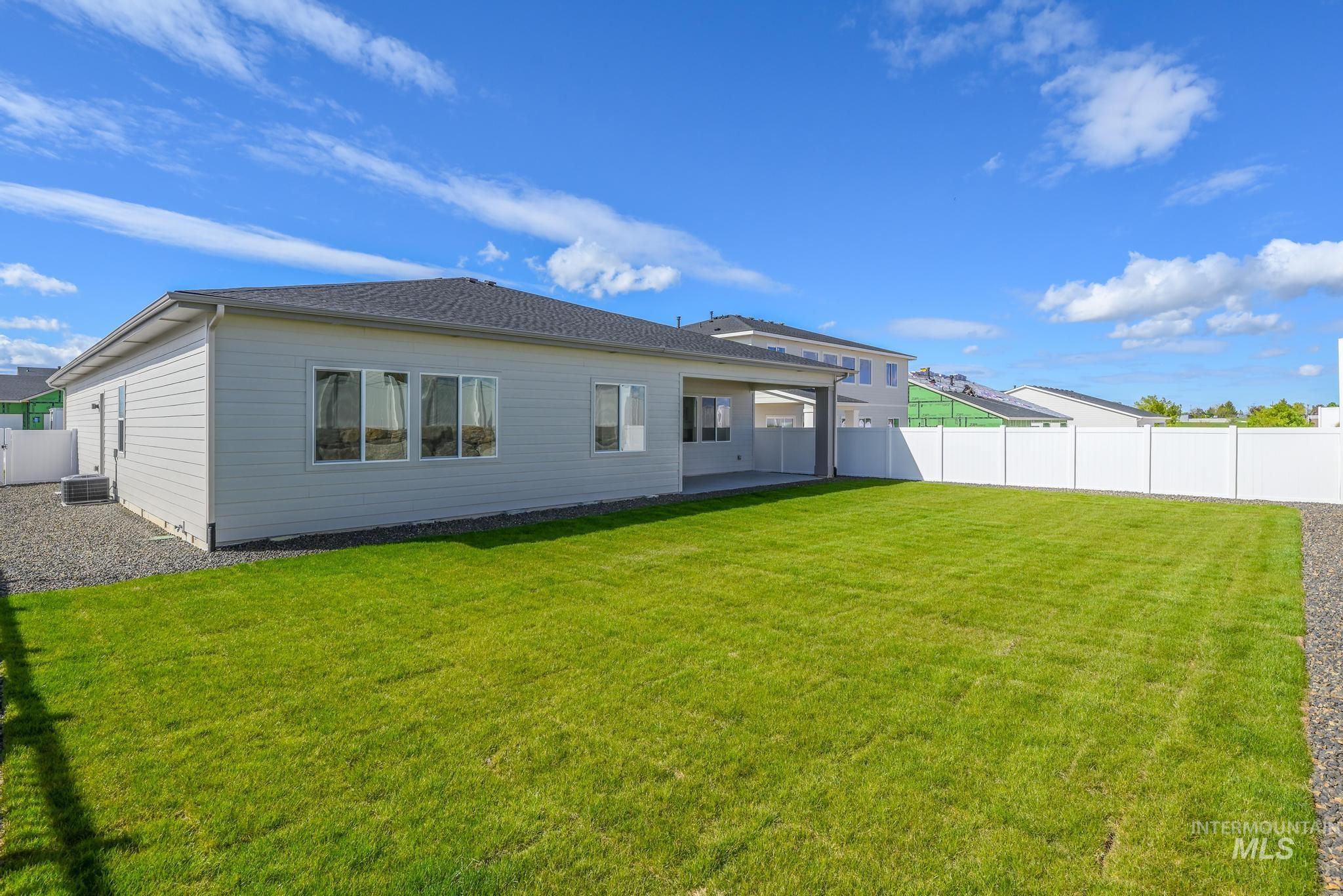 14676 Serenity Pt Street Caldwell, ID 83607 - Photo 31 of 41 Spacious backyard featuring a manicured lawn, a full white privacy fence, and a covered patio area