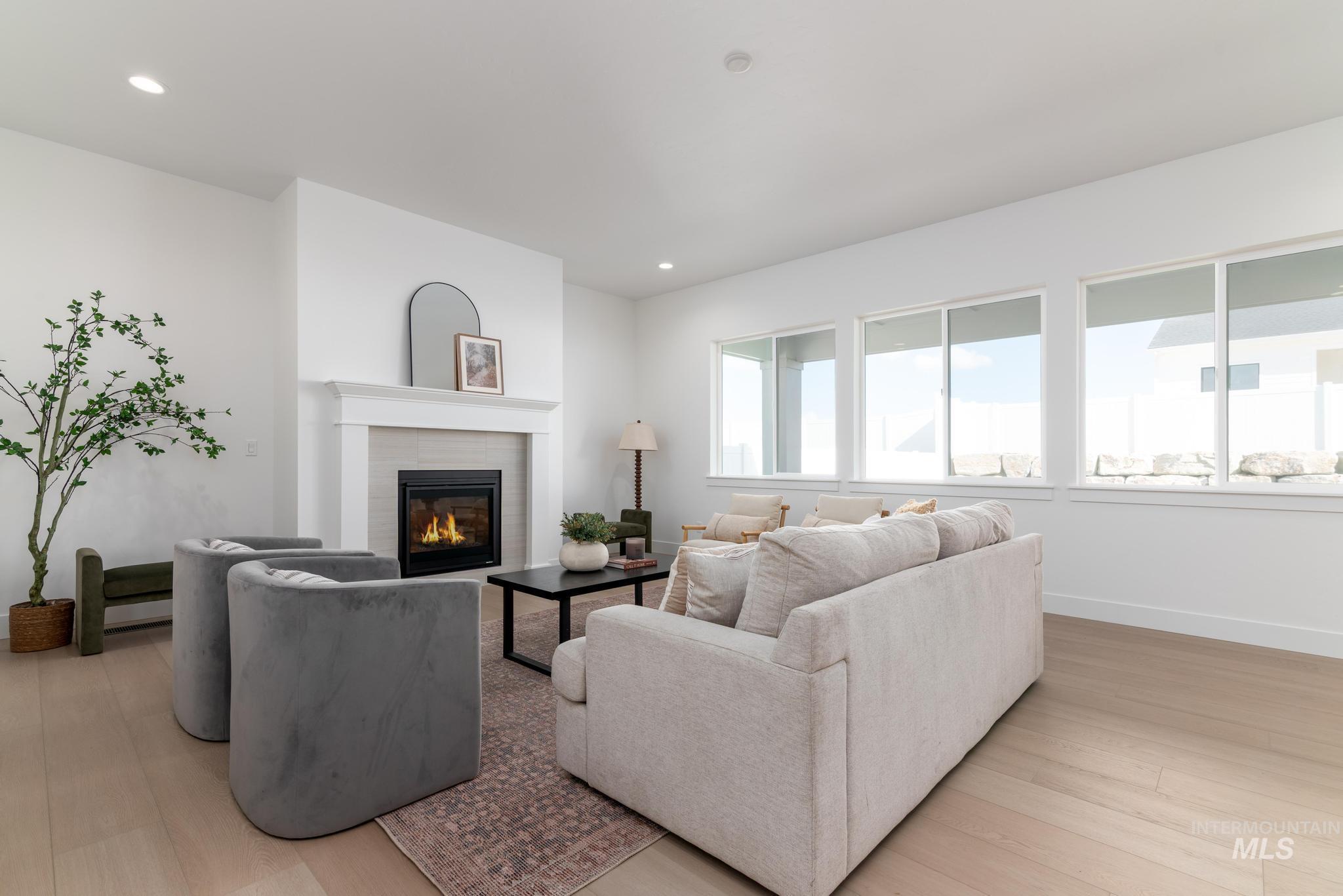 14676 Serenity Pt Street Caldwell, ID 83607 - Photo 6 of 41 Open-concept living space featuring a gas fireplace with a light-toned tile surround and a classic white mantel