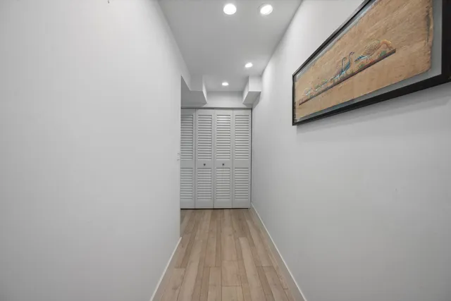 a view of a hallway with wooden floor and a bathroom