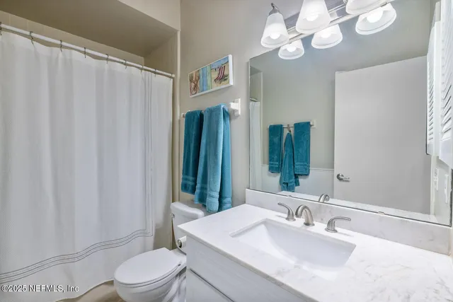 a bathroom with a sink a toilet a mirror a vanity and shower