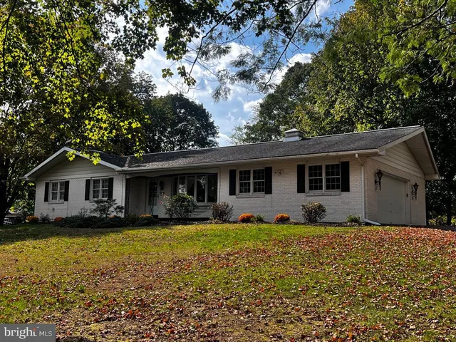 a front view of house with yard and trees in the background