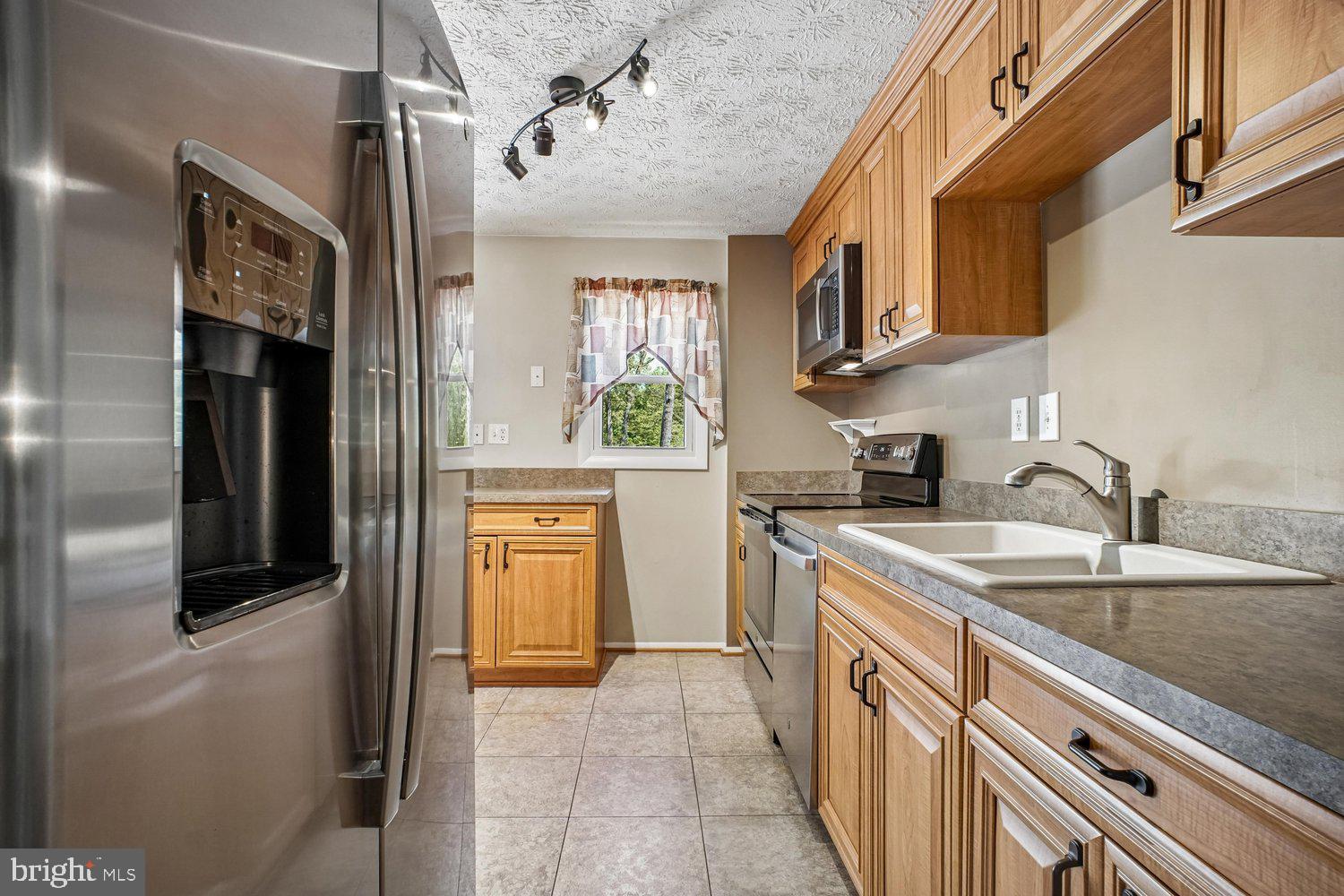 8491 Rippled Creek Court Springfield, VA 22153 - Photo 15 of 40 a kitchen with stainless steel appliances granite countertop a sink and a refrigerator