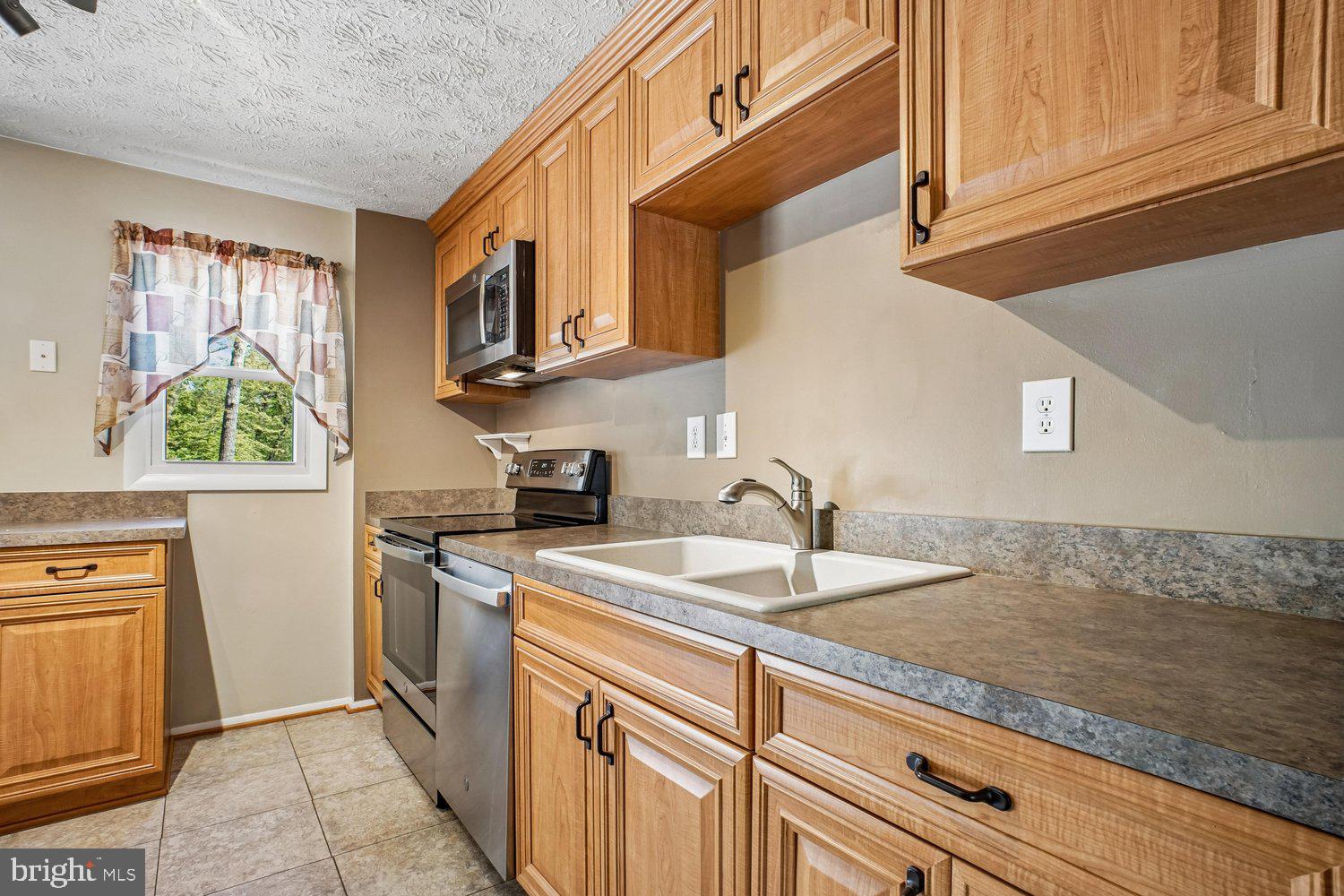 8491 Rippled Creek Court Springfield, VA 22153 - Photo 16 of 40 a kitchen with stainless steel appliances granite countertop a sink a stove and a refrigerator