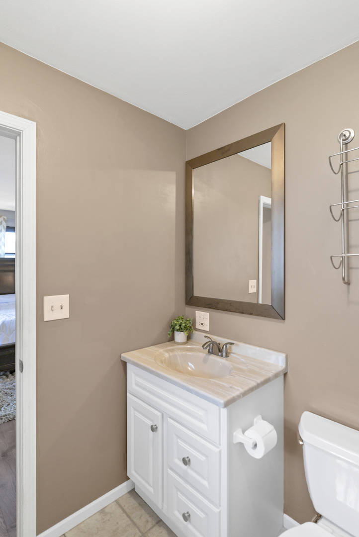 103 Fir Street Lake In The Hills, IL 60156 - Photo 14 of 31 a bathroom with a toilet a sink a vanity and mirror