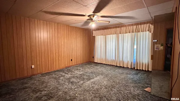 an empty room with a ceiling fan and windows