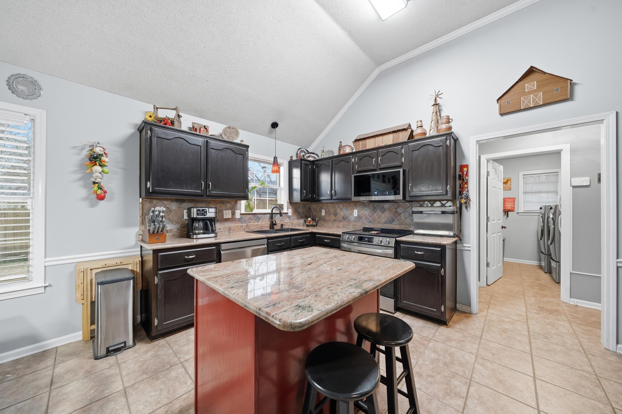 307 John Cove Collierville, TN 38017 - Photo 22 of 25 Kitchen with backsplash, light stone counters, a breakfast bar area, light tile patterned flooring, and lofted ceiling