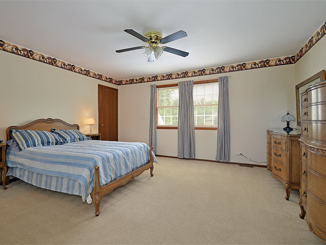 587 Scots Court Inverness, IL 60067 - Photo 9 of 18 a spacious bedroom with a large bed and a chandelier